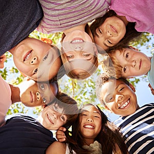 Group of kids outdoors looking down at camera, square format