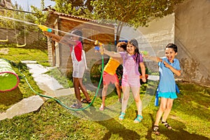 Group of kids play fun wet game with water guns