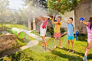 Group of kids play fun wet game with water pistols