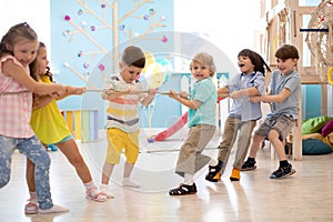 Group of kids play and pull rope together in daycare