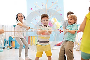 Group of kids play and pull rope together in daycare