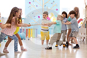 Group of kids play and pull rope together in daycare