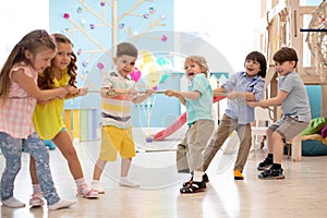 Group of kids play and pull rope together in daycare