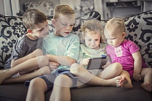 Group of kids playing with an electronic tablet devices photo