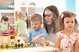 Group of kids playing with teacher in kindergarten