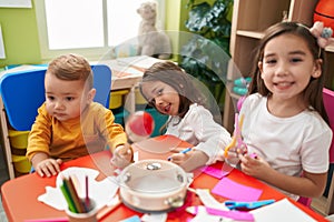 Group of kids preschool students sitting on table playing maraca and making handcrafts at kindergarten