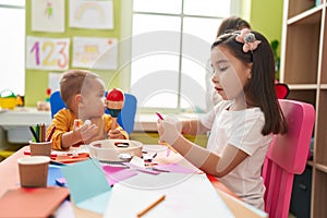 Group of kids preschool students sitting on table playing maraca and making handcrafts at kindergarten