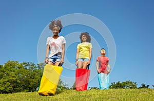 Group of kids race in bags downhill on the lawn