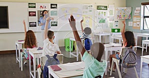 Group of kids raising their hands in the class at school