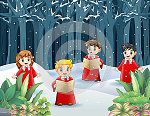 Group of kids in red costume singing Christmas carols on the snowy forest