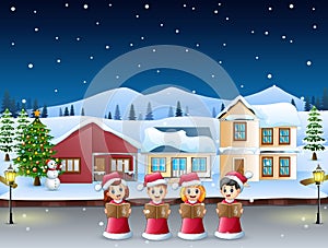 Group of kids in red santa costume singing christmas carols in the snowy village