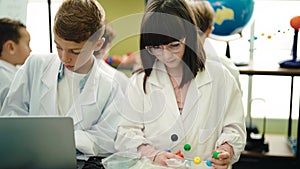 Group of kids scientists students using laptop holding molecules at laboratory classroom