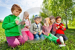 Group of kids sit in the field with magnifier