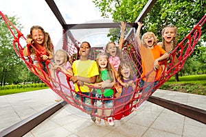 Group of kids sitting on playground net ropes photo