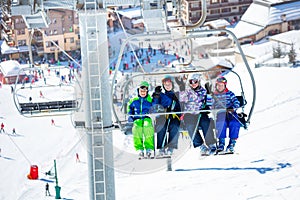 Group of kids on ski chairlift with crowded resort