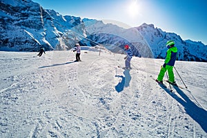 Group of kids ski downhill in the mountains