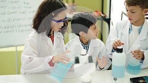 Group of kids students pouring liquid on bottl doing experiment at laboratory classroom