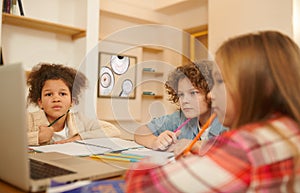 A group of kids studying remotely together and writing something down