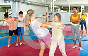 Group of kids training self-defence moves in gym