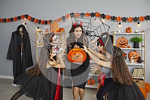 Group of kids trying to frighten their teacher at a fun Halloween party at school