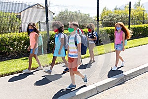 Group of kids wearing face masks walking on footpath
