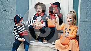 Group of kids wearing halloween costume putting sweets in pumpkin basket at street