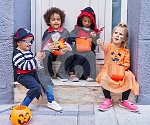 Group of kids wearing halloween costume putting sweets in pumpkin basket at street