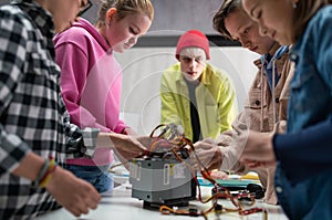 Group of kids working together on project with electric toys and robots at robotics classroom