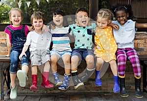 Group of kindergarten kids friends arm around sitting and smiling fun