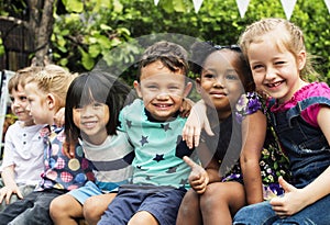 Group of kindergarten kids friends arm around sitting and smiling fun