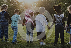 Group of kindergarten kids friends holding hands playing at park