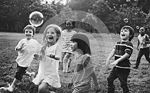 Group of kindergarten kids friends playing blowing bubbles fun