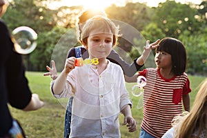 Group of kindergarten kids friends playing blowing bubbles fun