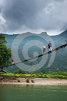 Group of Laotian high school girls across the simple suspension footbridge