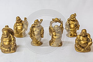 Group of Laughing Buddha painted in gold colour in a white backdrop. Macro with extremely shallow depth of field