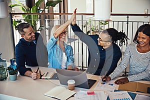 Group of laughing coworkers high fiving during an office meeting