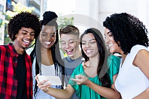 Group of laughing latin american and african young adults watching clip