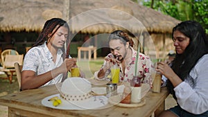 Group of lgbtq friends enjoy tropical drinks at beach hut. Mixed gender pals laugh, share stories, savor summer day