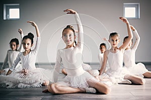 Group of little ballerinas girls doing exercises in dance school