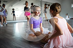 Group of little ballerinas girls doing exercises in dance school