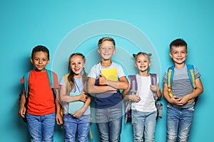 Group of little children with backpacks school supplies on color background