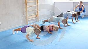 Group of little children doing push-ups on sports mats during a self-defense class in a gym