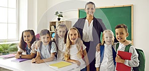 Group little children posing together with female primary school teacher after finishing lessons