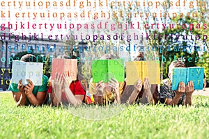 Group of little children reading books on grass in park