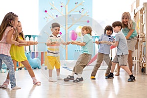 Group of little kids play and pull rope together in competition