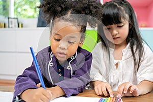 Group of little preschool kids drawing paper with color pencils . portrait of African girl with friends education concept.