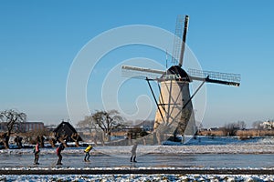 Group of locals on a frozen windmill canal pathway at sunrise moment