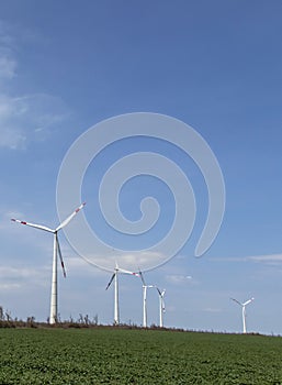 Group of low angle view of wind turbine towers again cloudy blue sky at the wind farm. Green, sustainable renewable energy concept