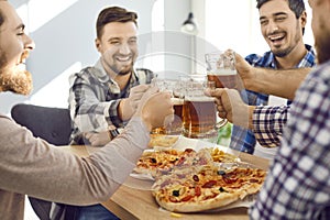 Group of male close friends eating pizza and drinking beer