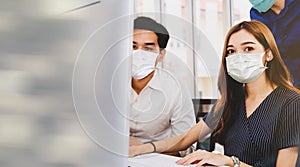 Group of male and female colleagues put on medical faces during office work to prevent epidemic.